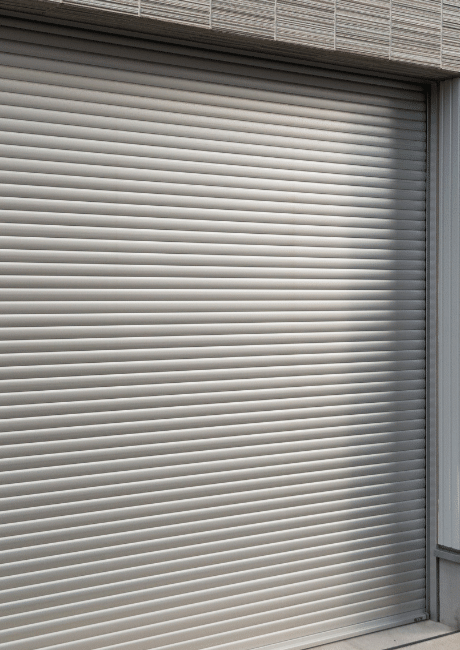Closed grey roller garage door on a building with a tiled awning above