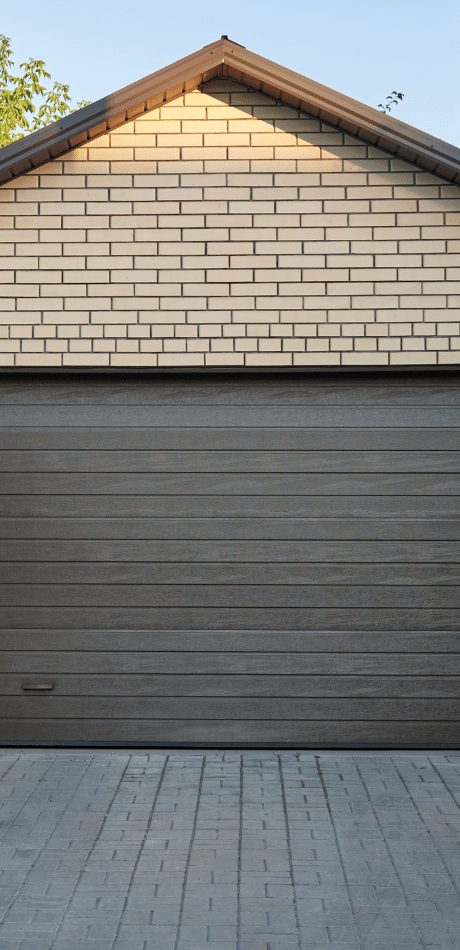 Dark wood-grain garage door beneath a cream brick gable on a house