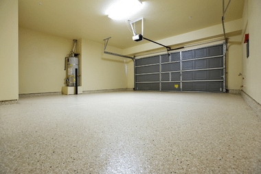 Empty garage interior with epoxy-flake flooring and a closed sectional door
