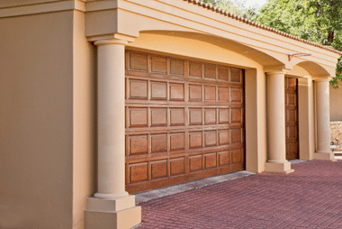 Dark wood panelled garage door beneath a stone archway entrance