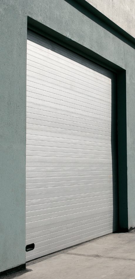 Grey roller garage door recessed into a stucco building entrance