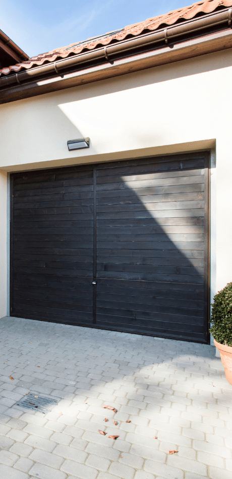 Dark timber-look double garage door on a cream stucco house with terracotta roof tiles