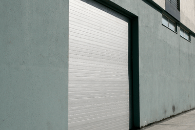 White roller door on a green-painted building exterior wall