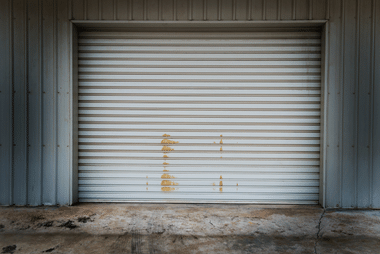 White roller door with weathered rust staining on a corrugated metal shed