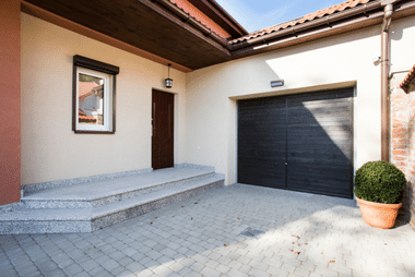 Dark wood double garage door on a stucco house entrance beside the front door and steps