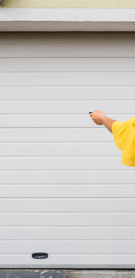 Person in a yellow top pointing a remote control at a white roller door