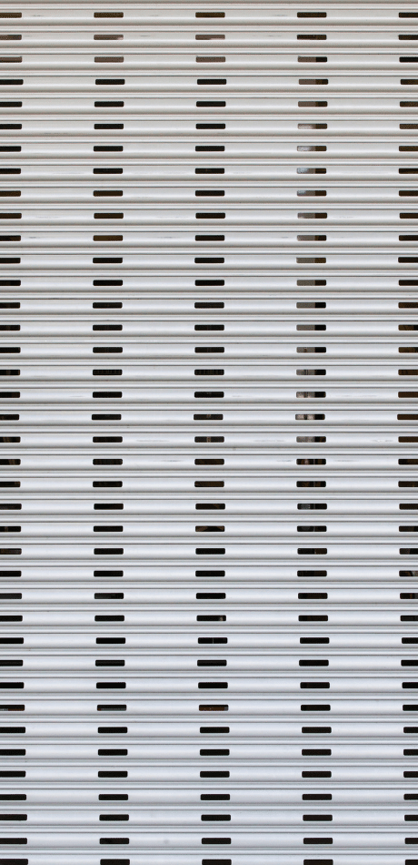 Close-up of a white roller door's ribbed slats showing the horizontal profile and small vent slots.