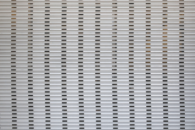 Close-up of a ridged aluminium roller door surface with rows of narrow slots.
