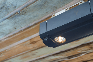 Garage door opener light illuminated on a ceiling-mounted rail