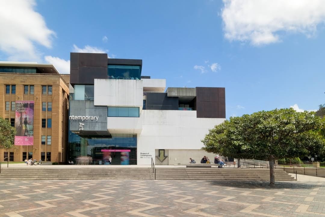 Angular modern museum building with a large geometric facade, a paved plaza and steps in front.